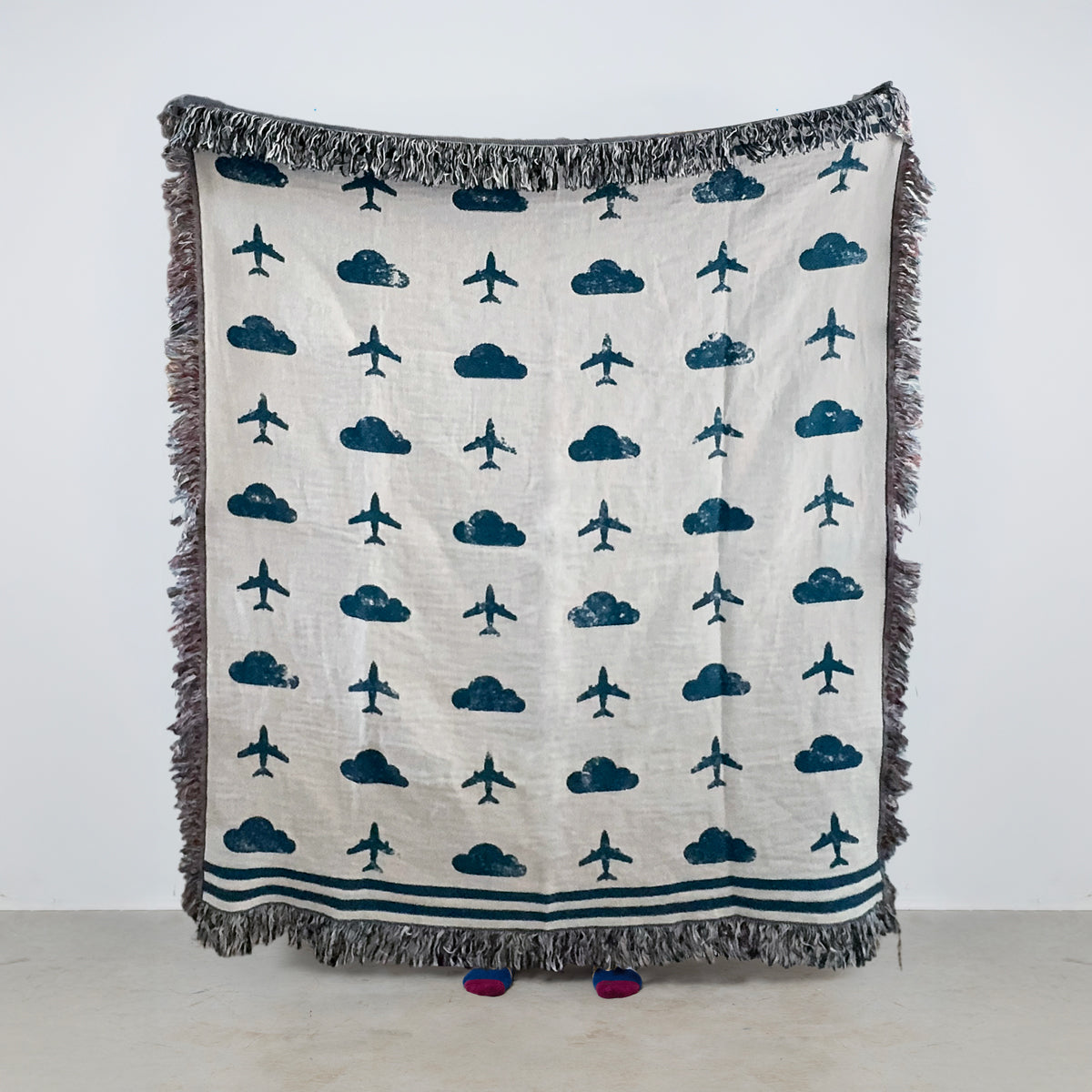 Blue and off-white woven aviation blanket with repeating airplane and cloud pattern for pilot and aviation enthusiast home décor.