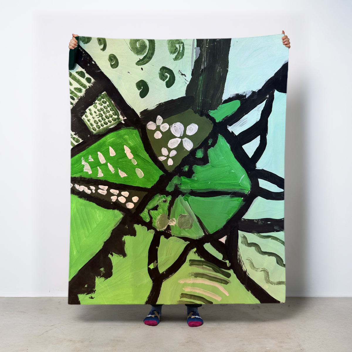 Person holding a large abstract painting with green, black, and blue colors. Add your own child's artwork.
