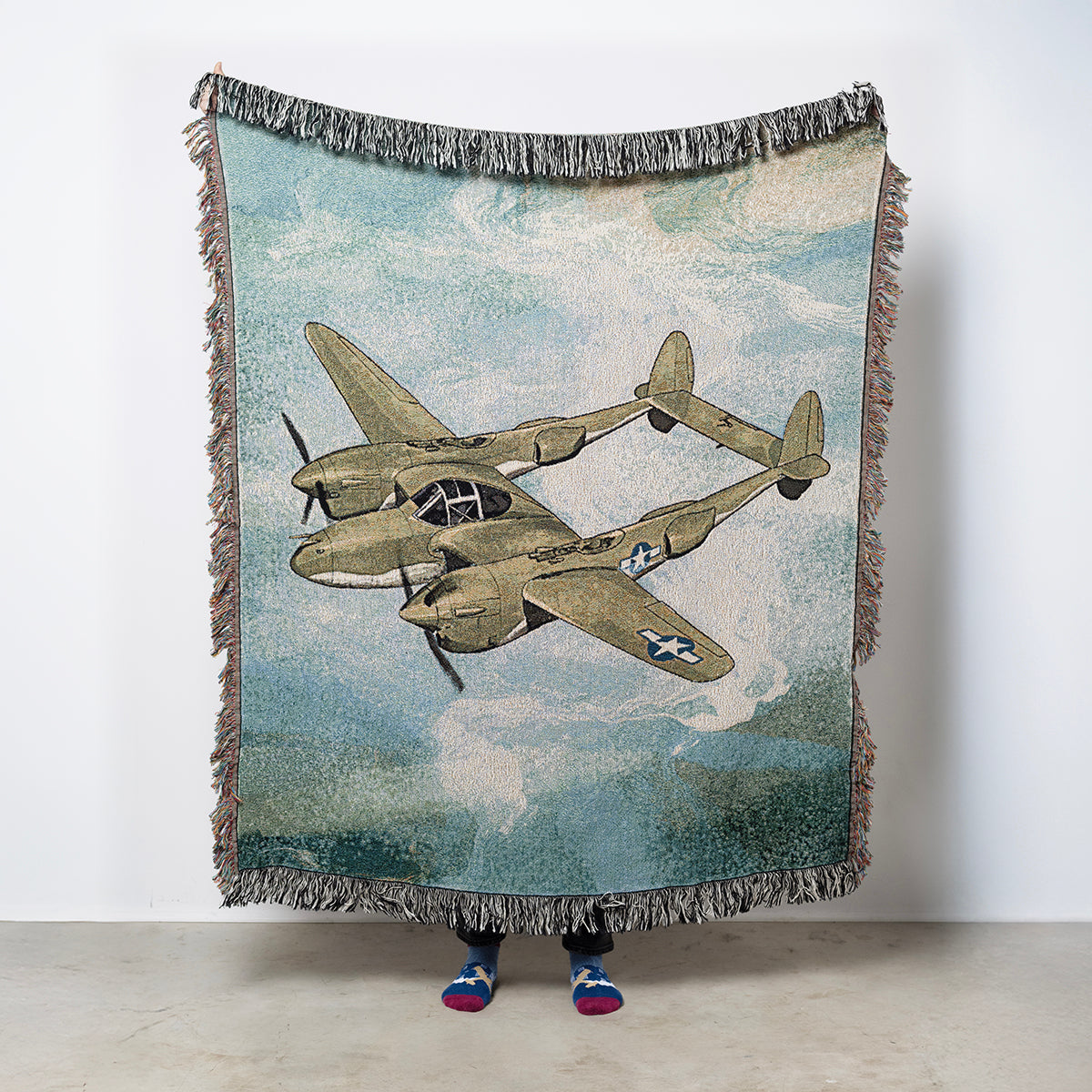 Woven blanket with vintage P-38 Lightning airplane design against a sky background