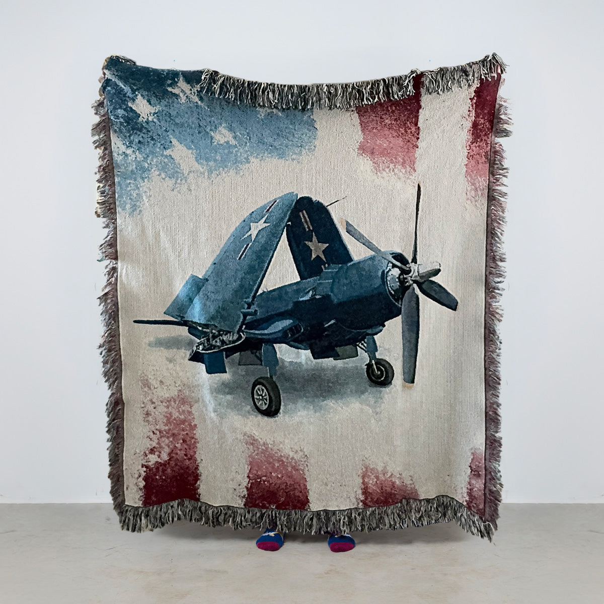 Woven blanket with a vintage Vought F4U Corsair airplane design on an American flag background