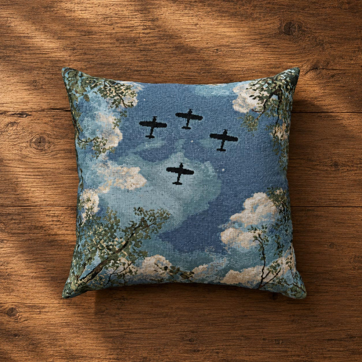 Under Wings Above aviation throw pillow featuring four airplanes flying overhead through a blue sky with soft clouds and leafy forest branches, matching woven aviation blanket design
