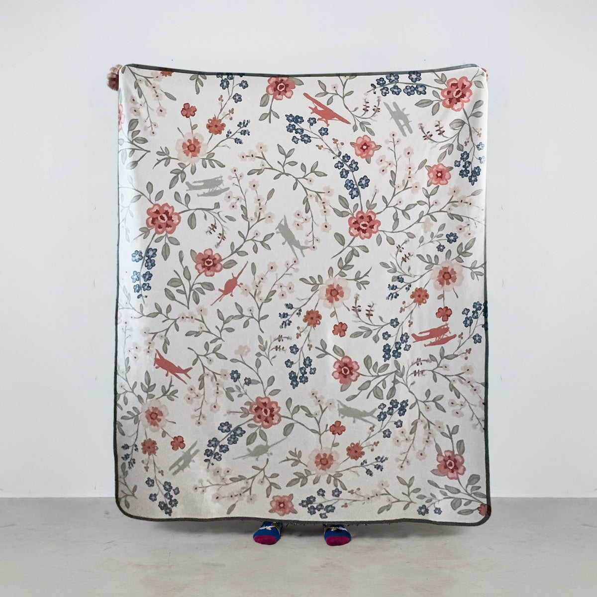 fleece blanket with floral pattern and general aviation airplanes on a cream background