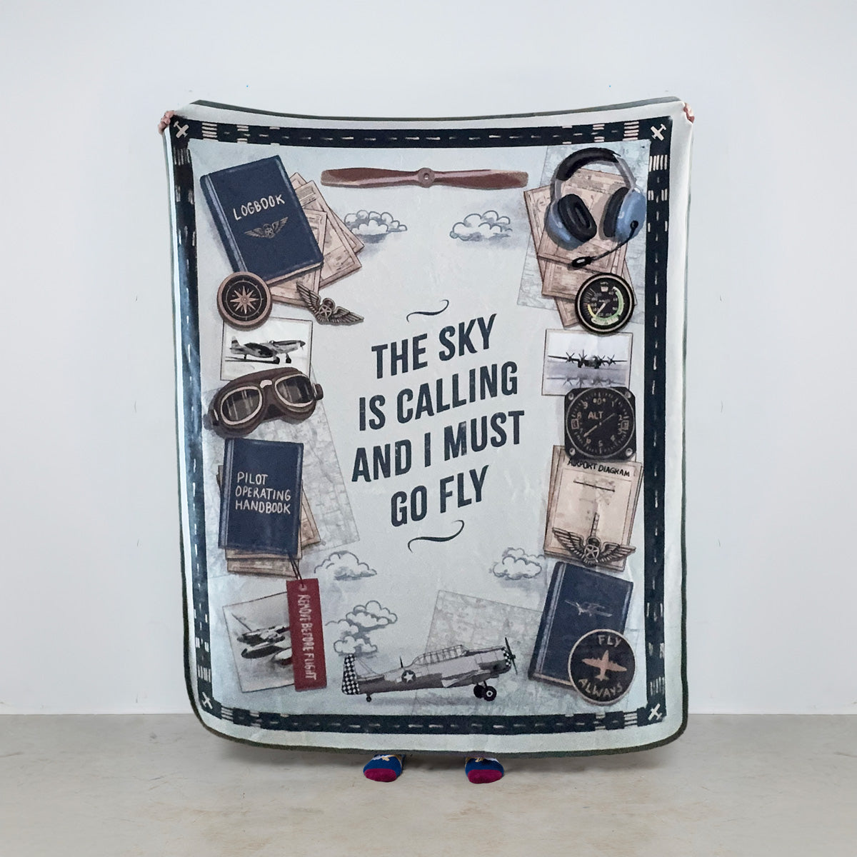 Fleece blanket with aviation-themed design and 'The sky is calling and I must go fly' text on a white background.