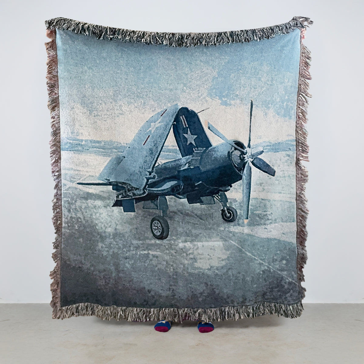 Woven blanket with a vintage Vought F4U Corsair airplane with wings folded design on an aircraft carrier background 