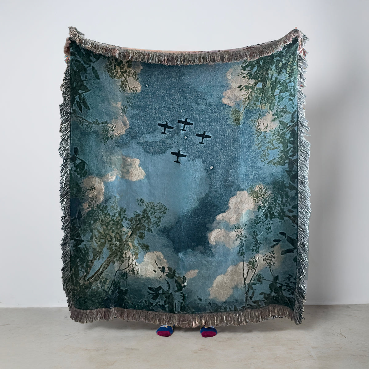 Decorative blanket with airplanes flying overhead looking through trees.