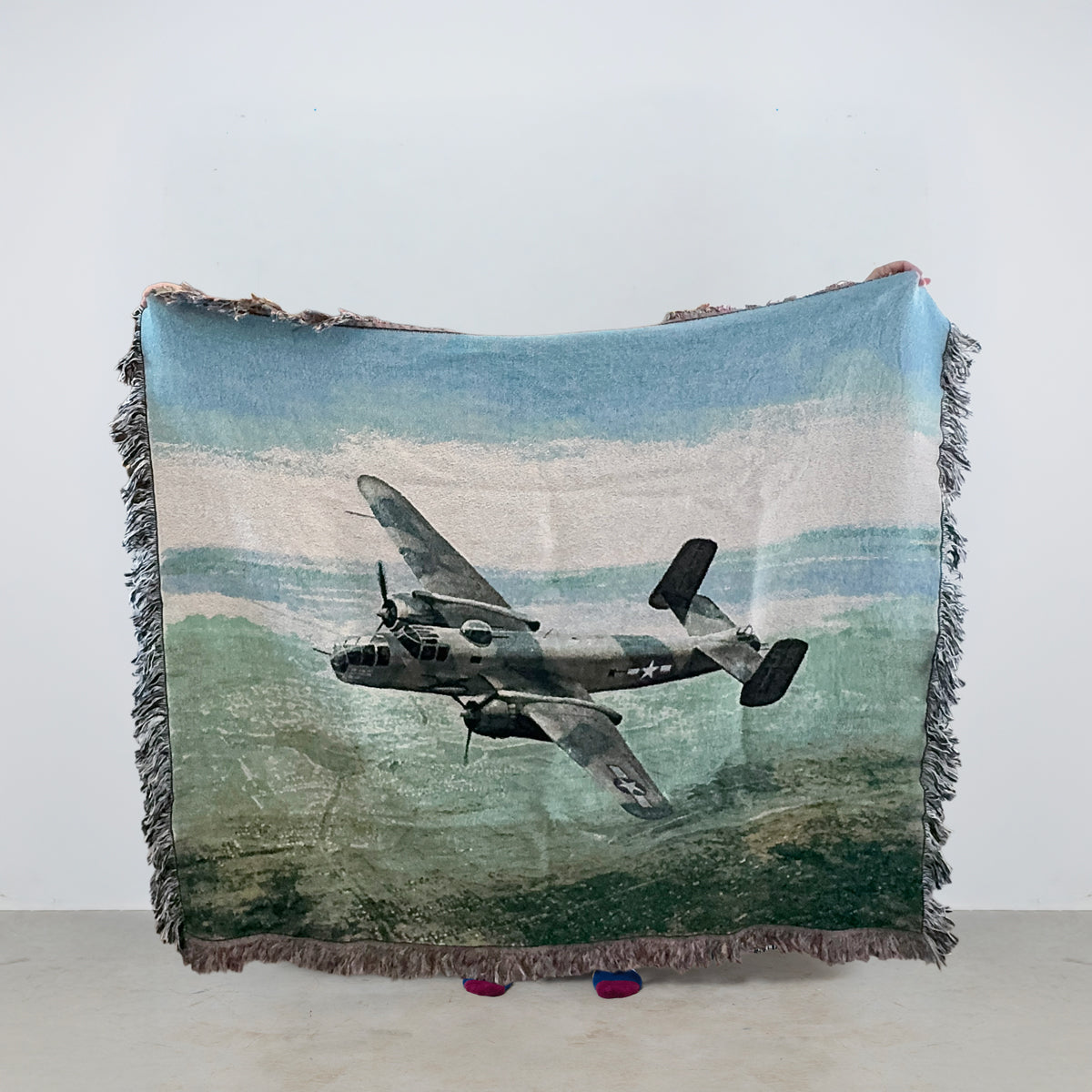Woven blanket with vintage B-25 airplane design flying over land