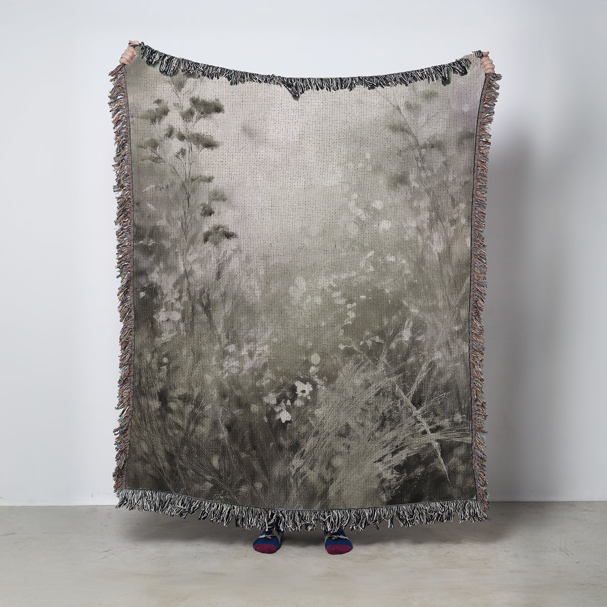 Woven blanket with nature-inspired design on a plain background