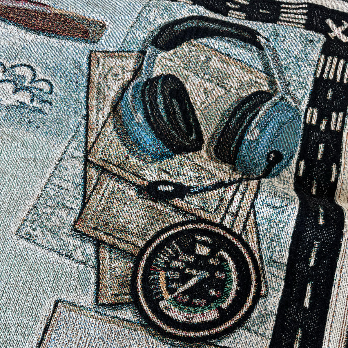 Close-up of a woven blanket with headphones and an airspeed indicator.
