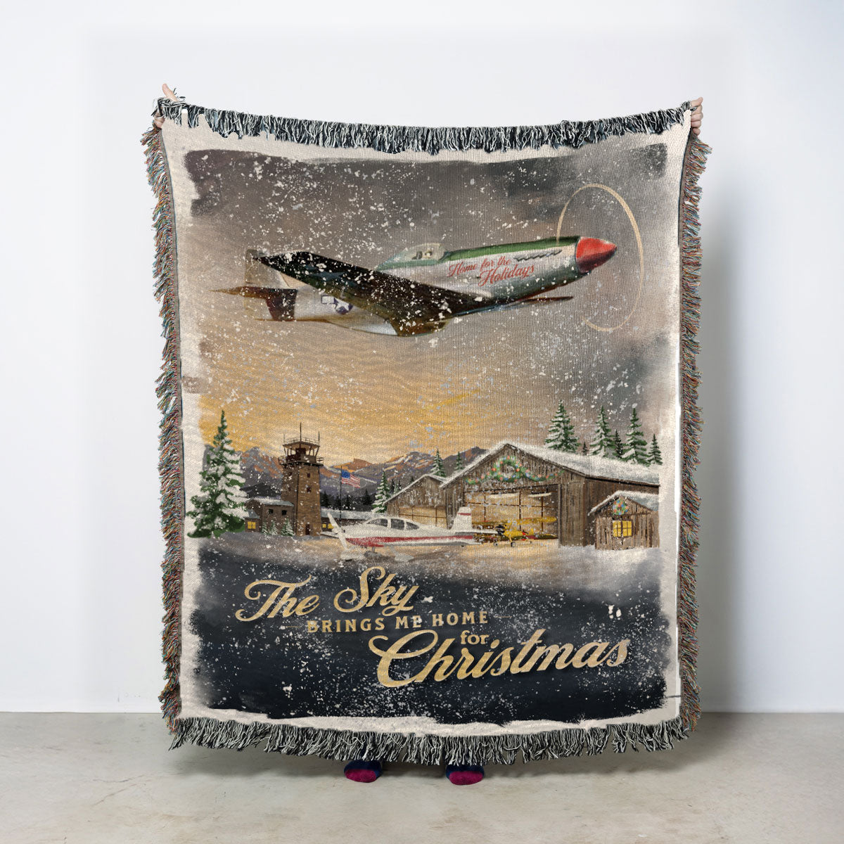 A vintage-style Christmas throw blanket with fringed edges, featuring an illustration of a flying airplane over a snowy airport scene and custom text.