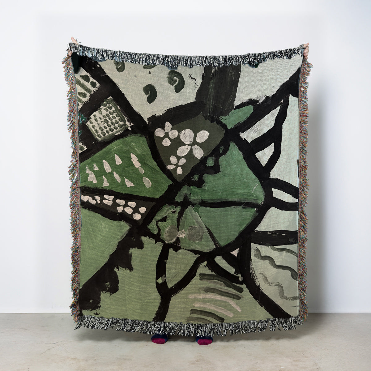 Abstract patterned blanket with green, black, and white design on a light background