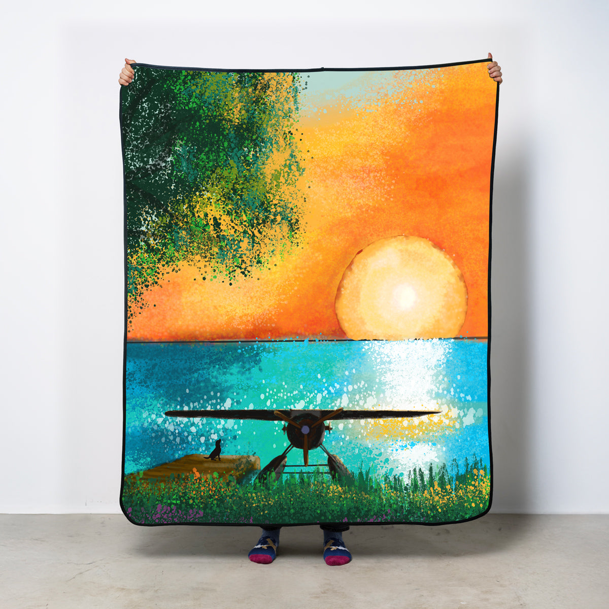 Colorful fleece blanket with a sunset and seaplane design.