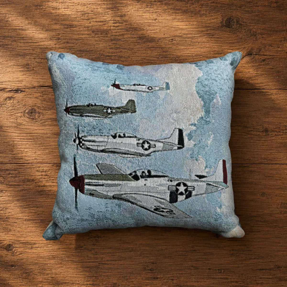 Four P-51 Mustang airplanes with different paint schemes flying in formation through a cloudy sky, featured on the Little Friends woven aviation pillow inspired by WWII fighter aircraft