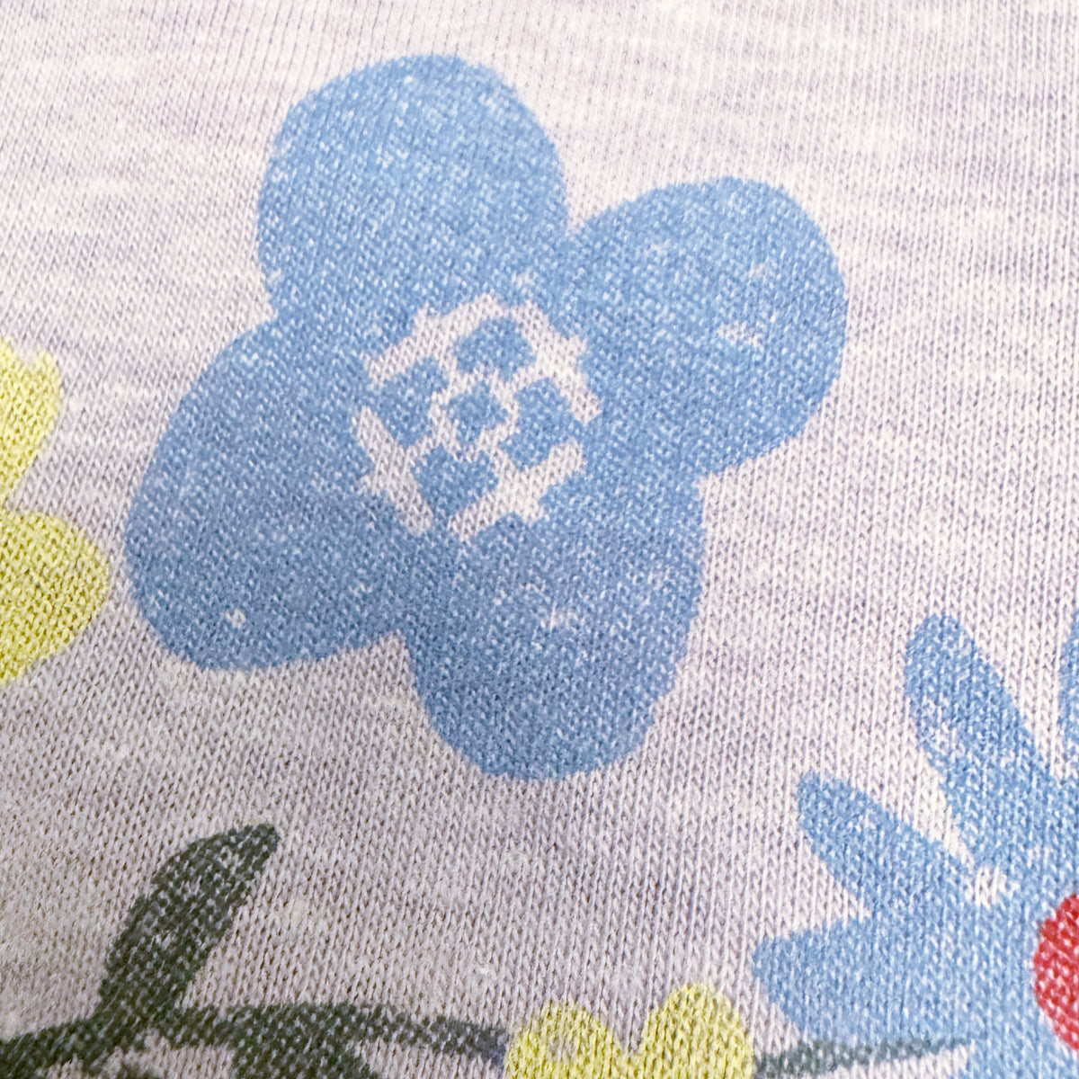 Close-up of floral airplane pattern with blue flowers on a lilac shirt