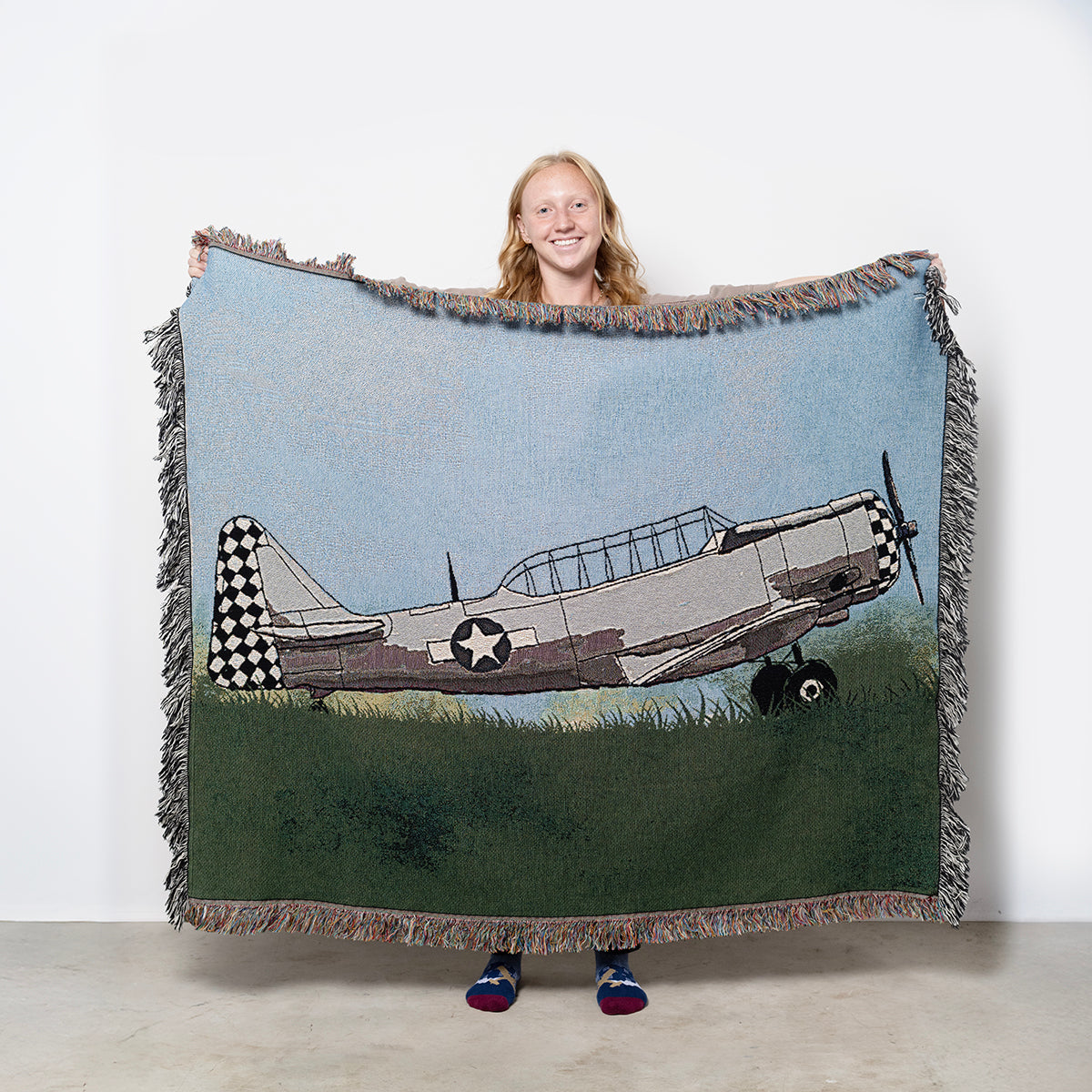 Woven blanket with a T-6 Texan Pilot Maker on grass with blue sky