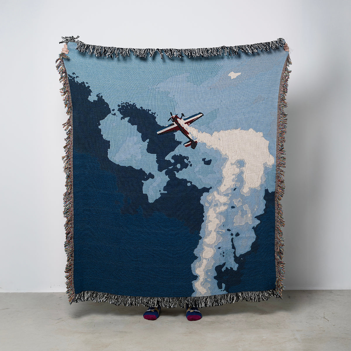 100% Cotton woven throw blanket with aerobatic airplane in the sky and clouds with smoke trail