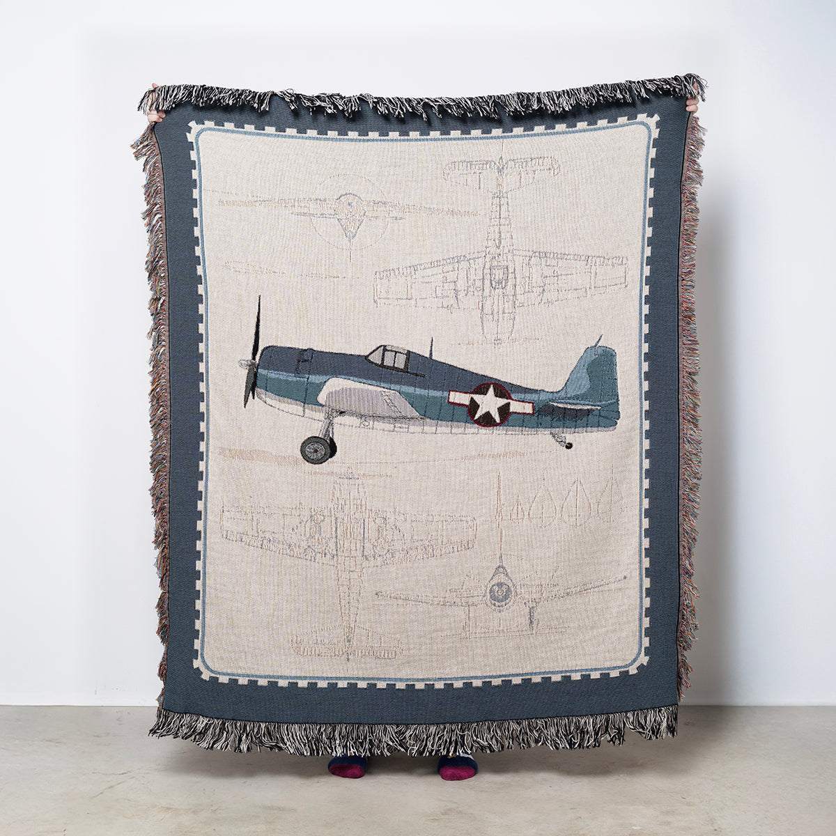 Blanket with Grumman F6F Hellcat airplane design and blue border on a light tan background