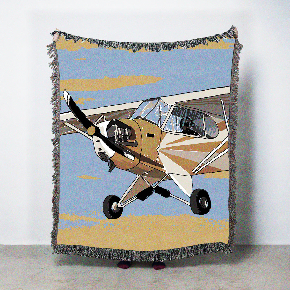 Woven blanket with a vintage airplane design on a blue and yellow sky background