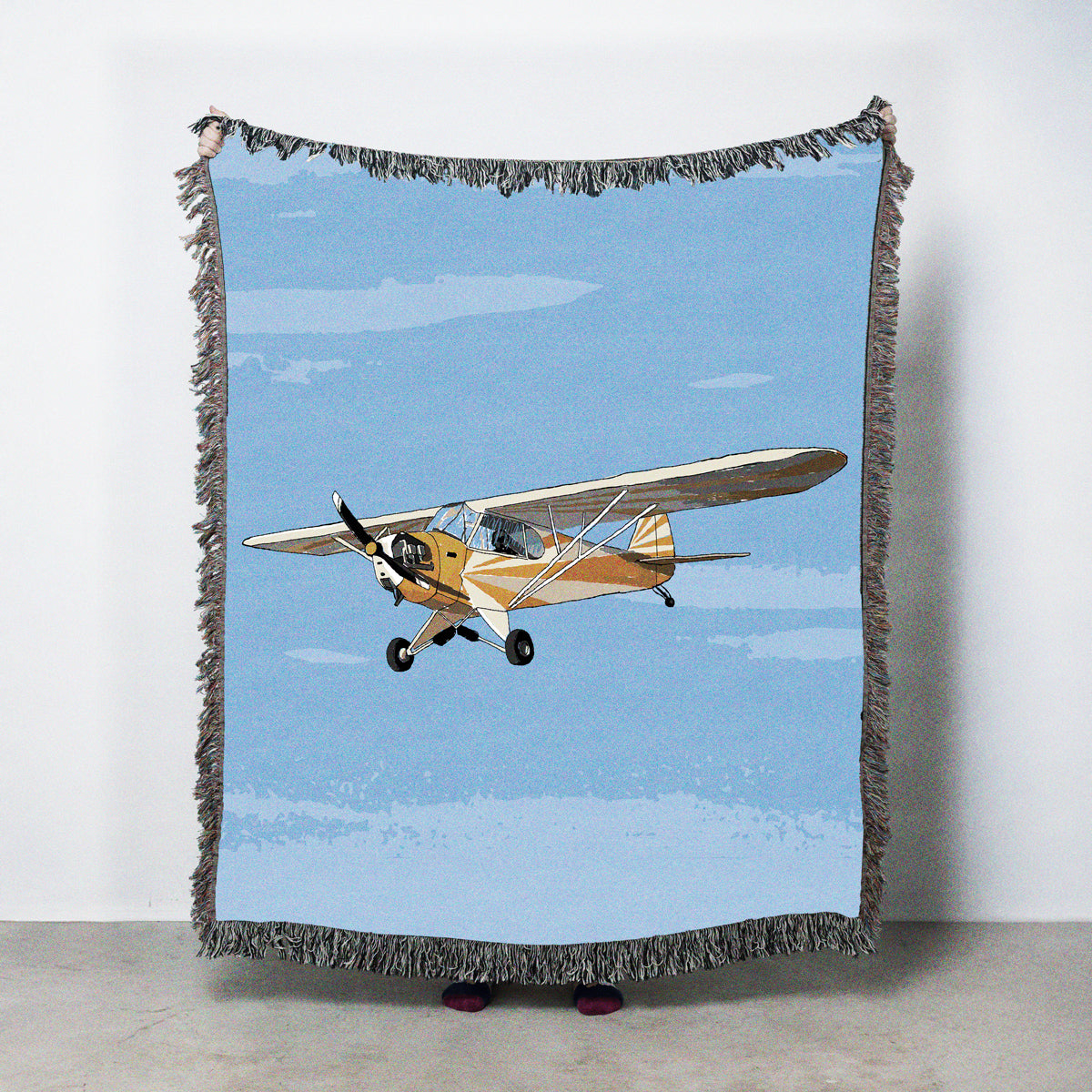 Blanket with a yellow airplane design against a blue sky background