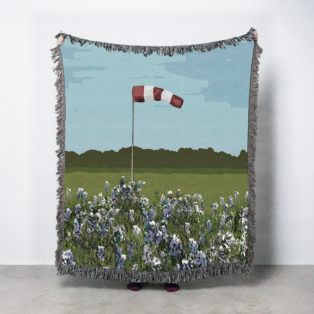 Blanket with a windsock design featuring a field of bluebonnets and grass