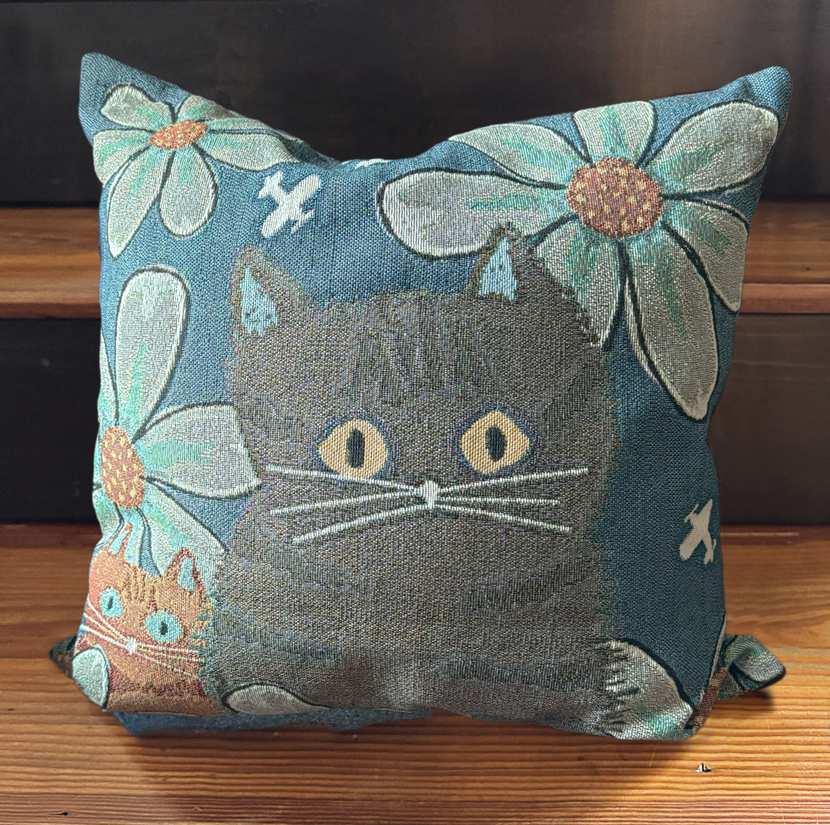 Decorative woven pillow with a cats and floral design on a blue background